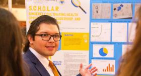 Texas Pharmacy student standing in front of his poster presentation board at the conference.