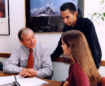 A student applicant is interviewed while a third person observes.