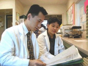 two pharmacy interns talking and wearing white coats