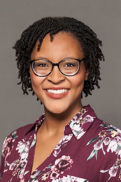 A woman wearing glasses and smiling.