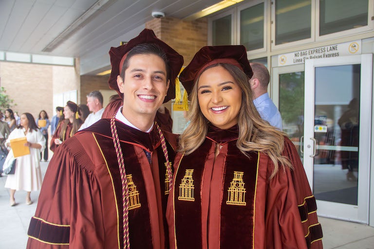 Two people in regalia smiling.