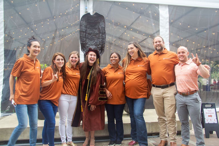 A group of people smiling in front of a statue.