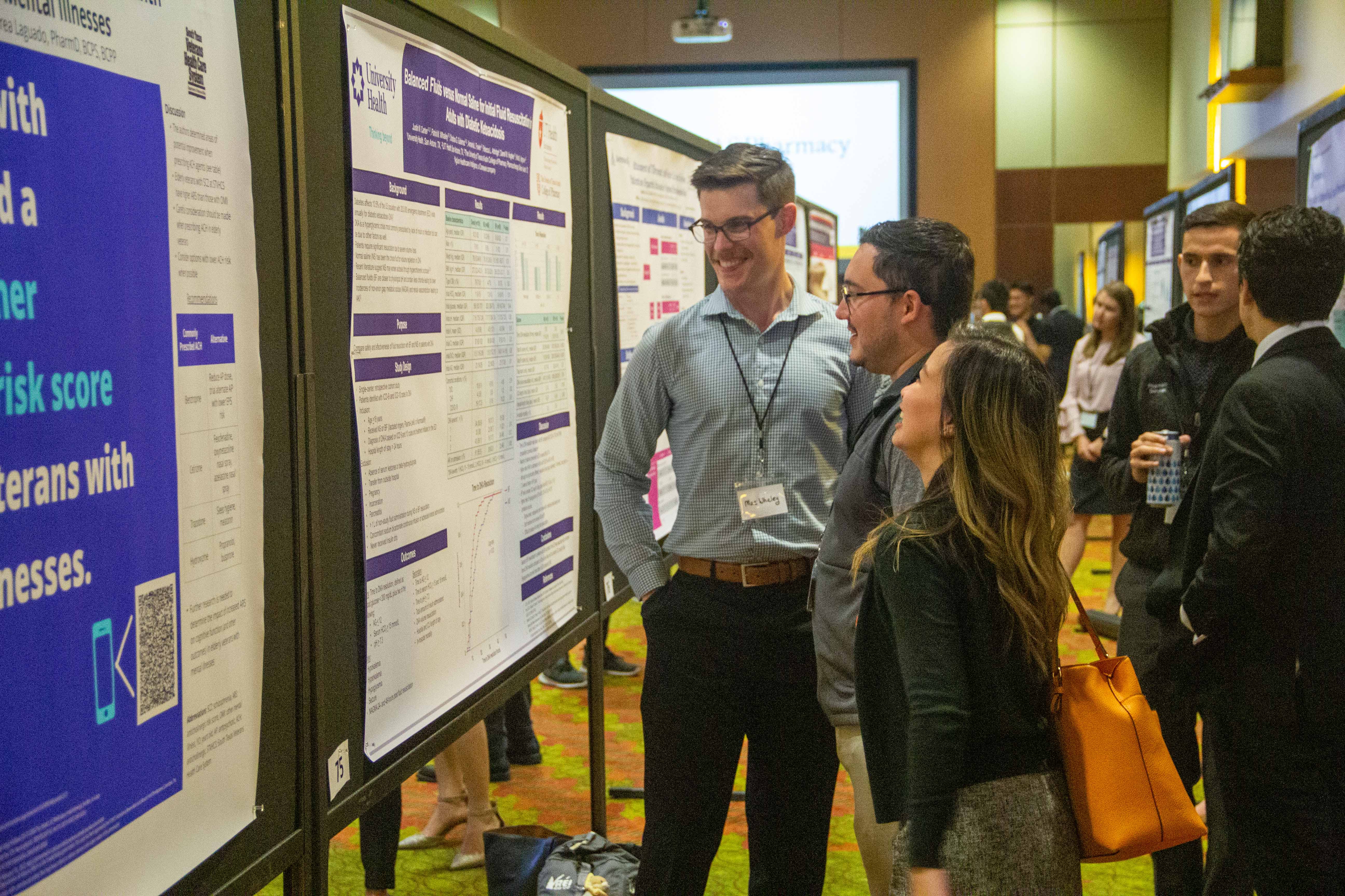 Two male and a female colleague in discussion in front of a science poster.