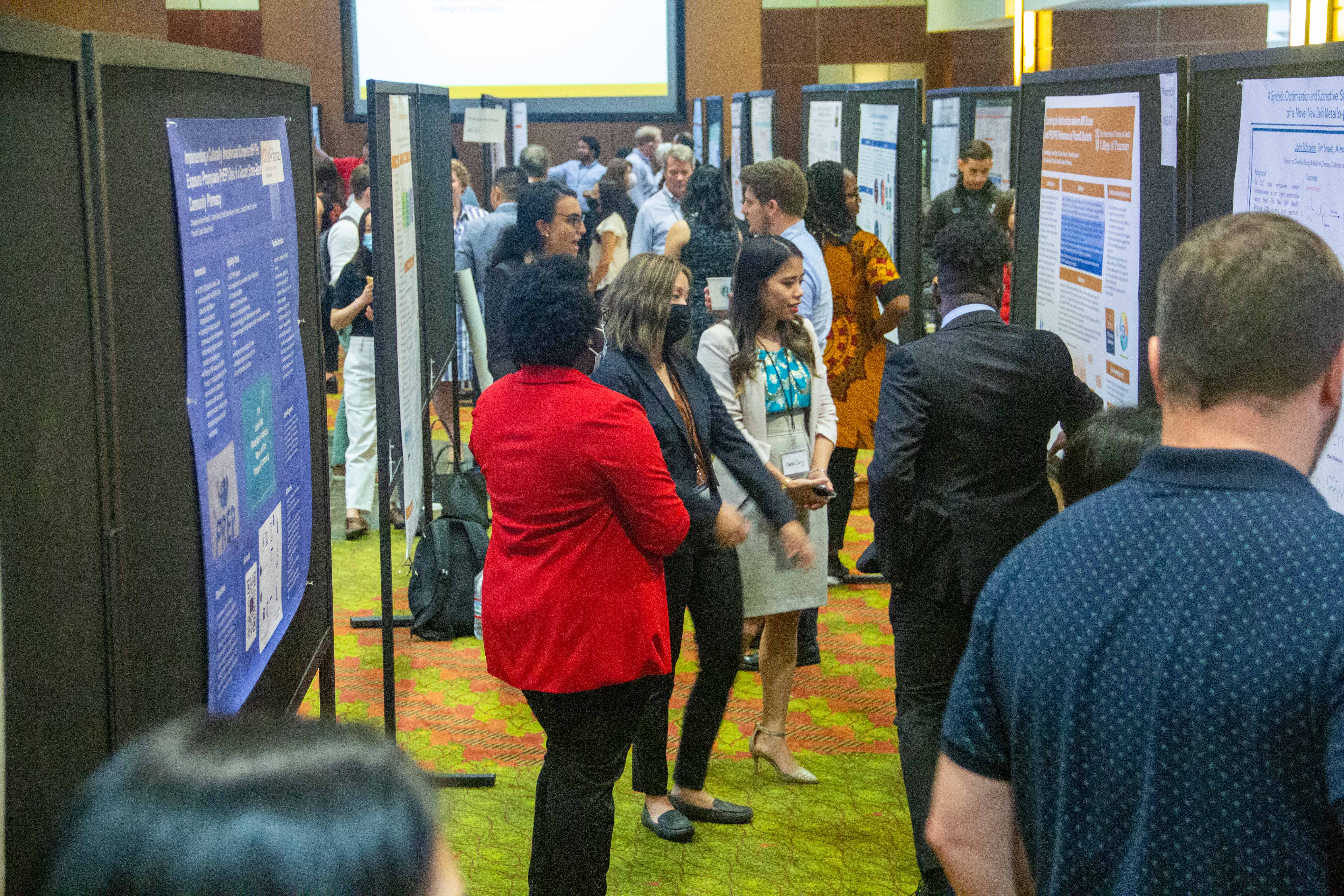 A busy room filled with people and scientific poster presentations.