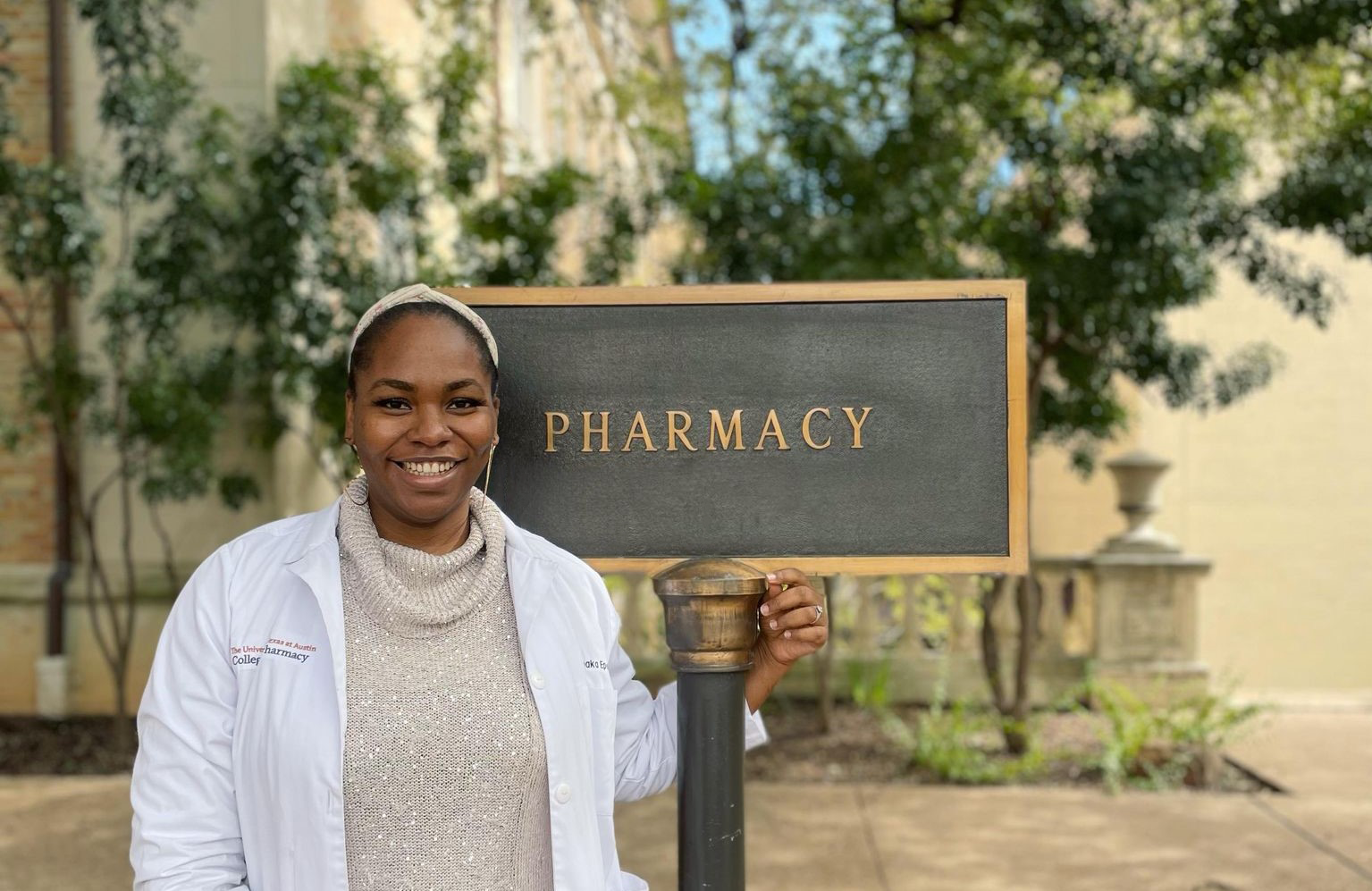 Pharmacy Student Amaka Epoh standing in front of the UT College of Pharmacy building sign.