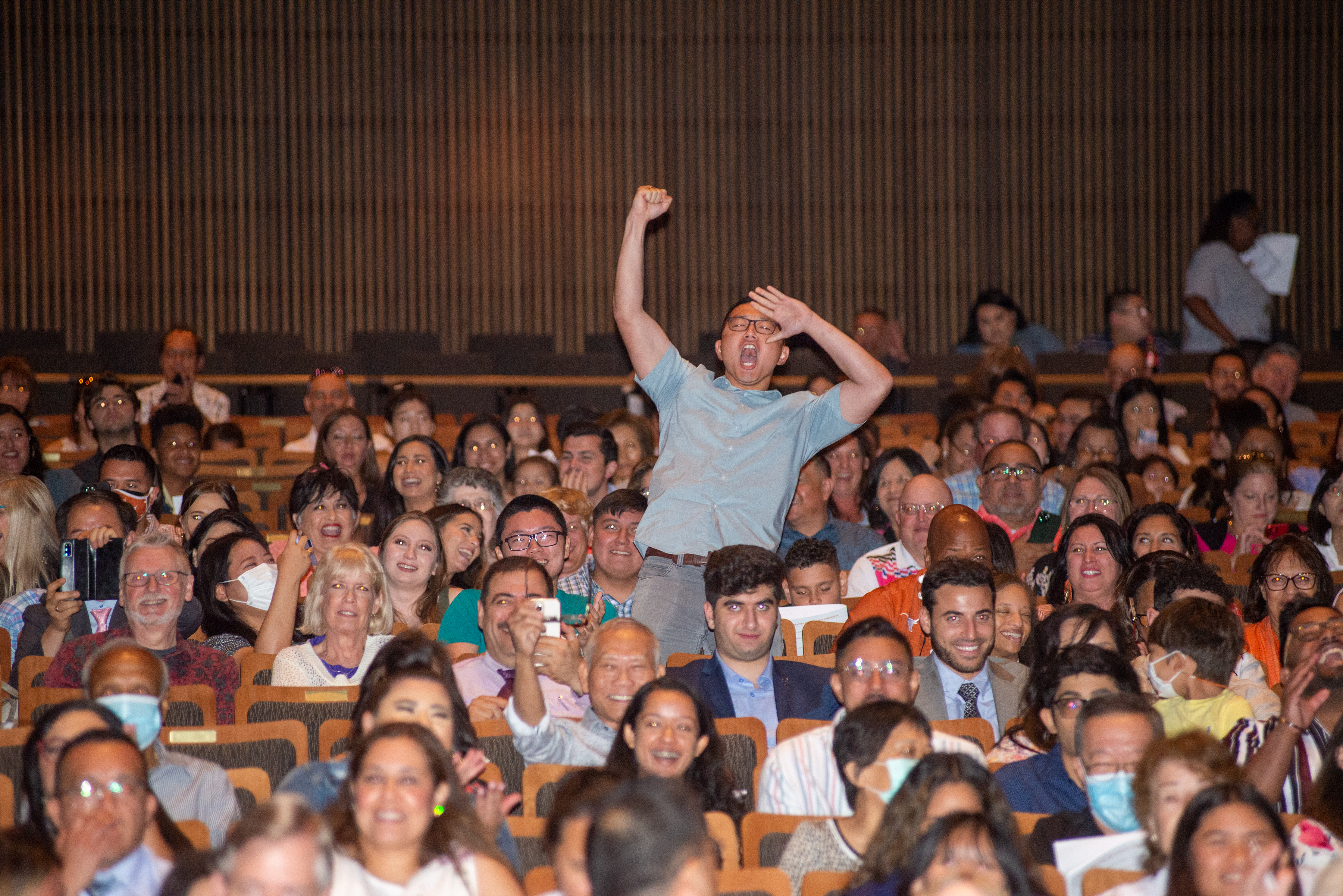 Audience member cheering in full auditorium.