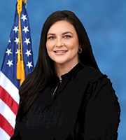 Dr. Kaitlen Shumate headshot photo with blue background and American flag