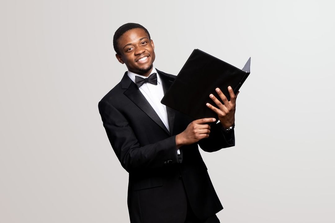 Bruno wearing a suit and holding a choir song book.