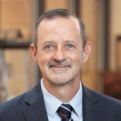 Dr. John Richburg smiling while wearing a suit and tie.