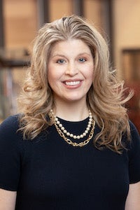 Dr. Moczygemba wearing necklaces and dark clothing and smiling.