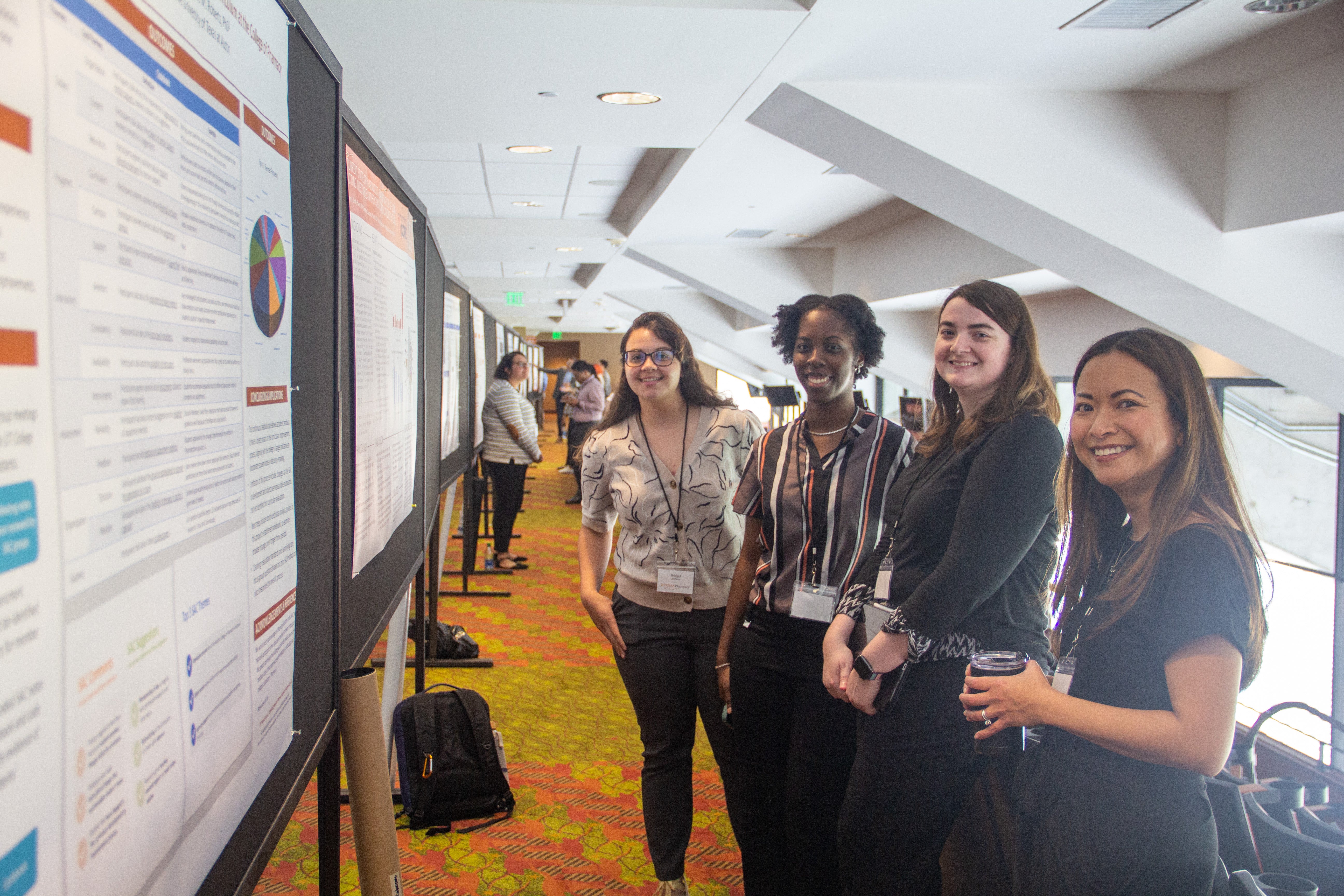 Texas Pharmacy faculty, student and staff standing near poster displays at Pharmacy Research Excellence Day.