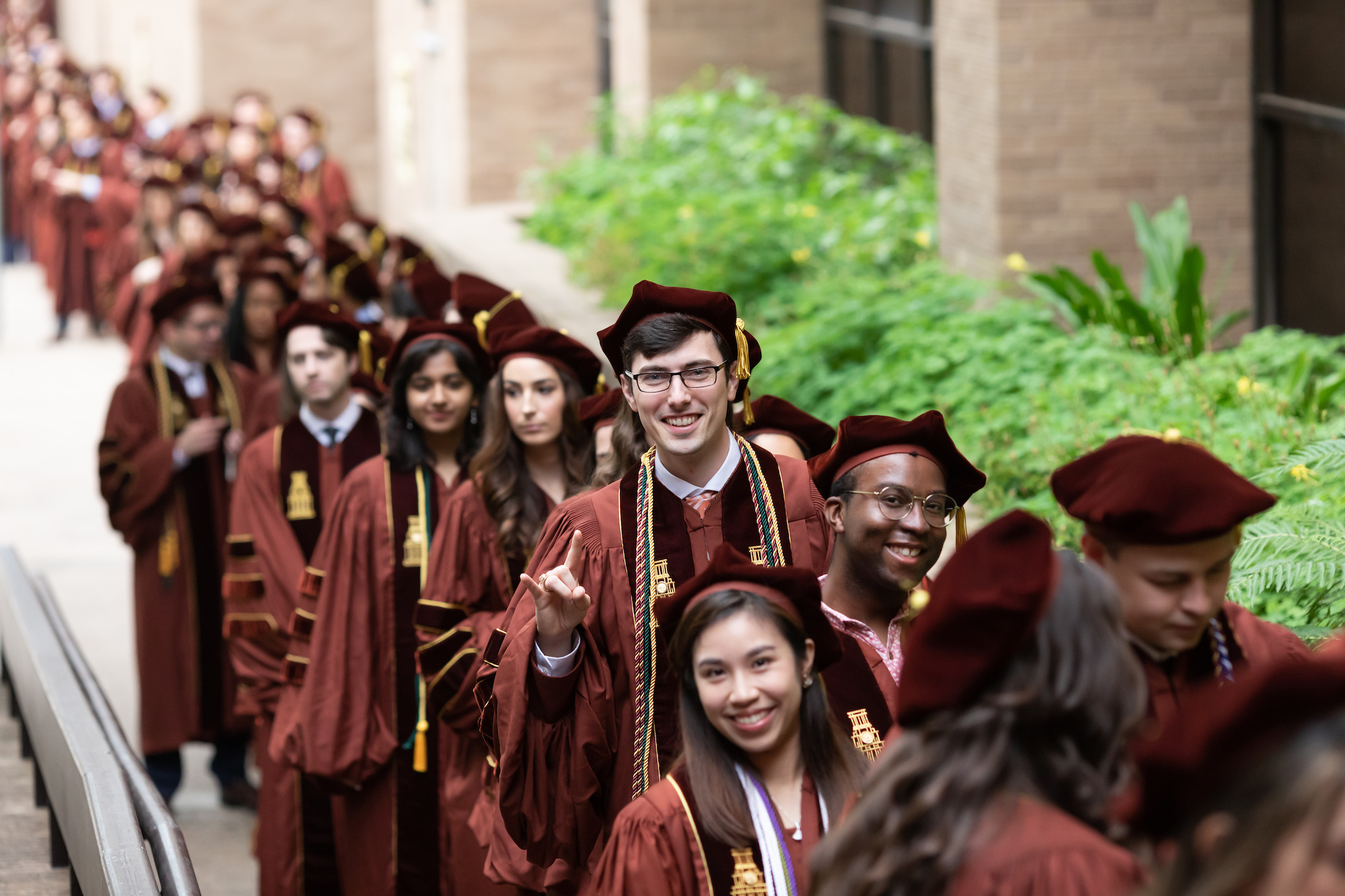 A long line of graduating students wearing caps and gowns.