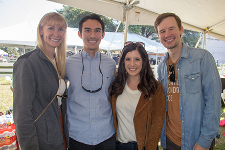 Four alumni smiling and standing in the homecoming tailgate tent