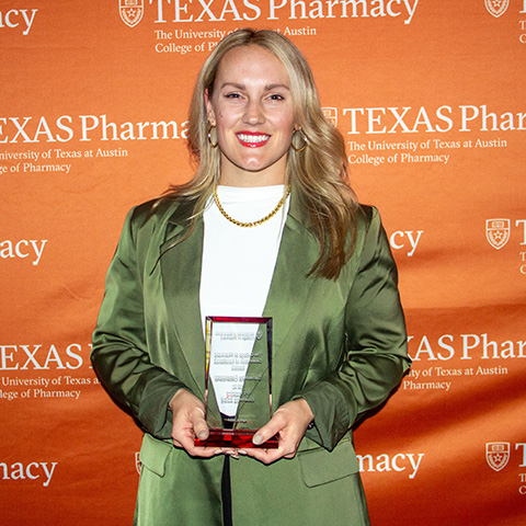 A woman holding an award and smiling.