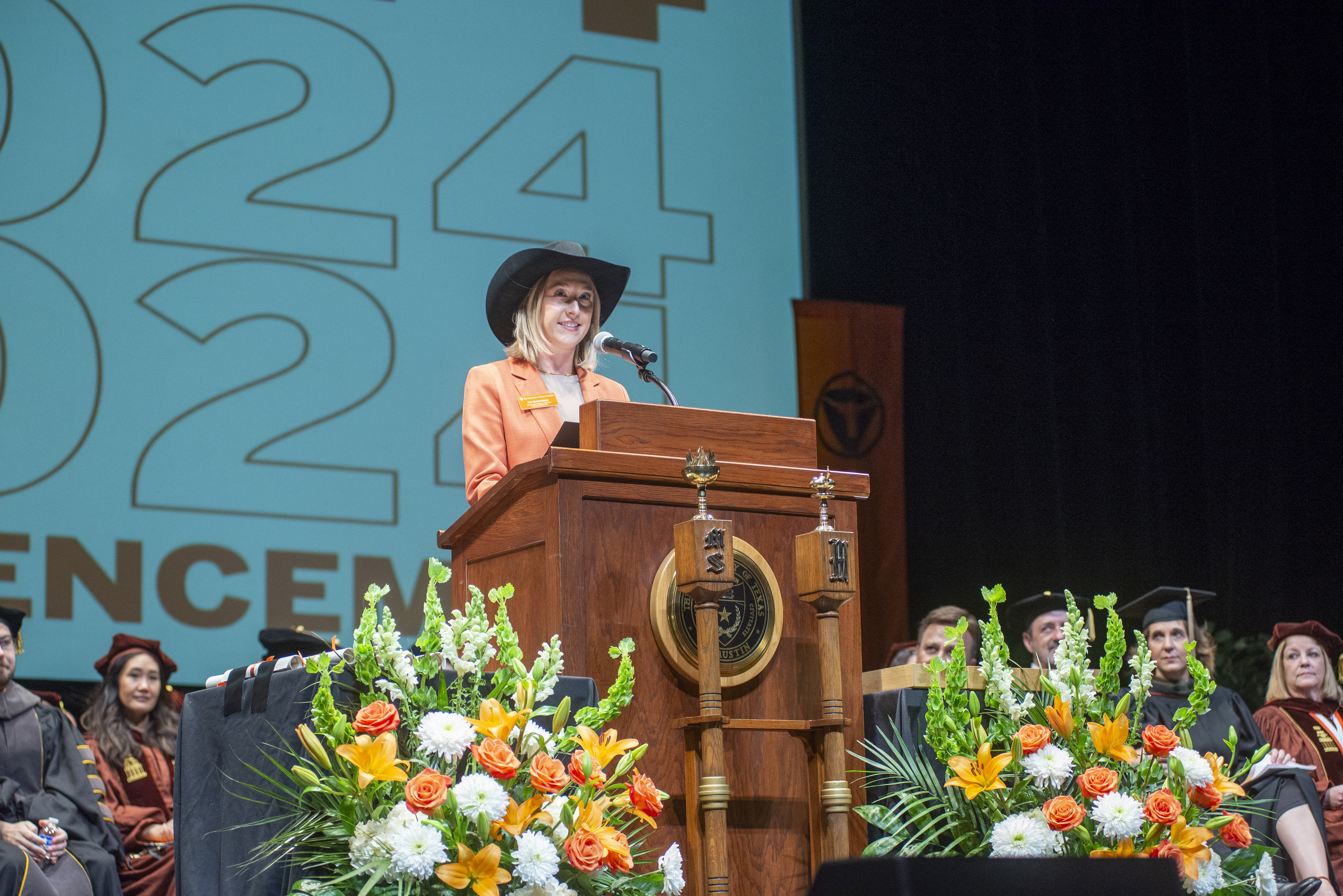 A woman wearing a cowboy hat and a burnt orange suit.