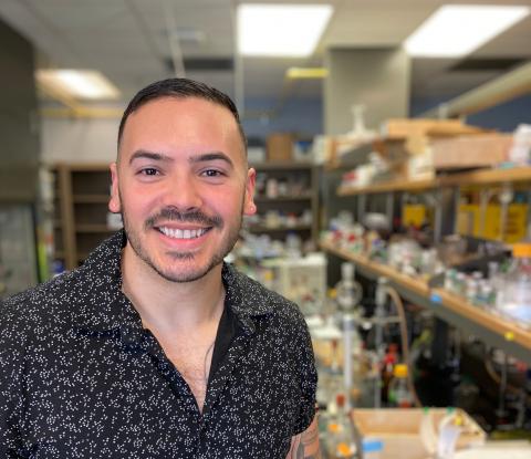 Leo smiling at the camera in while sitting in the lab.