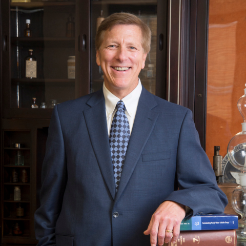 Dr. Bill Williams smiling at camera in a blue suit and tie.