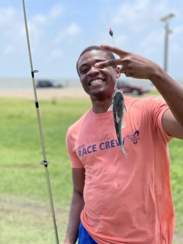 Bruno holding a fishing rod and a small fish he caught.