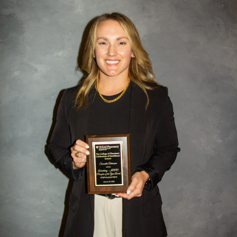 Dr. Catanzano holding her award plaque. She has straight blonde hair and is wearing a black top and blazer over taupe pants.