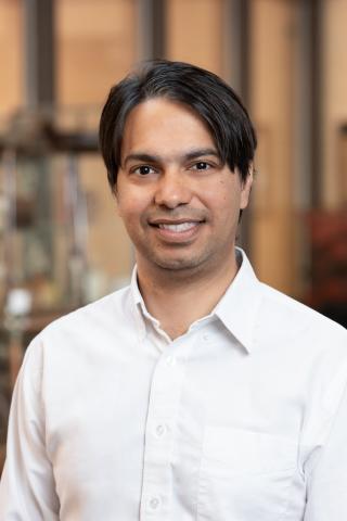 Dr. Mukhopadhyay wearing a collared shirt and smiling.