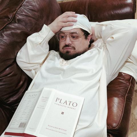 Student pharmacist Erik Coronado in a white dressing gown reading Plato.