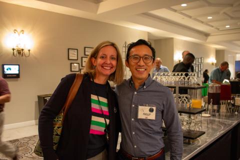 Dr. Cindy Gutierrez and Dr. Phillip Lai are standing next to each other and smiling for the camera. They are in the foyer outside of the classroom during a conference break.