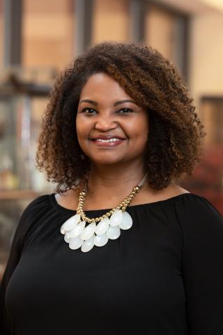 Headshot of Dr. Jamie Barner. She is wearing a black top and white and gold statement necklace.