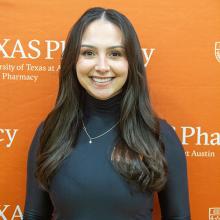 Alana Gonzales smiling in front of an orange UT Pharmacy background