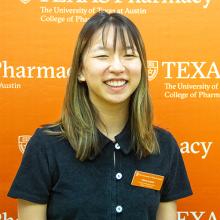 Olivia Laster smiling in front of an orange UT Pharmacy background