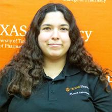 Sydney Saenz smiling in front of an orange backdrop