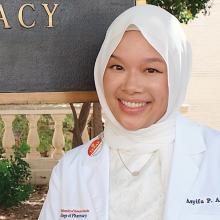 Asyifa Arcandra smiling in front of the Pharmacy building sign