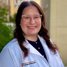 Kailey Bergdorf smiling and wearing a white coat in an outdoor setting
