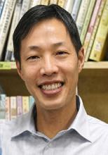 Dr. Mark Wong smiling in front of bookshelves