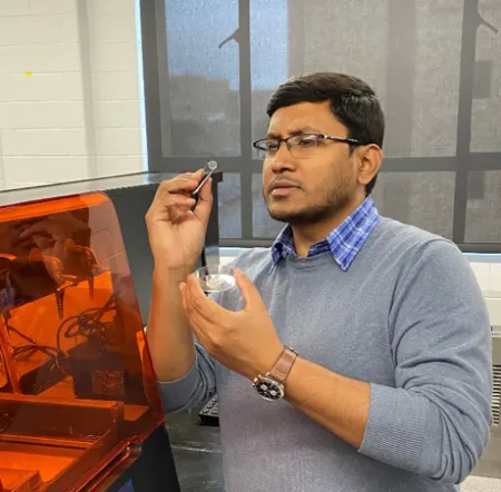 Dr. Maniruzzaman standing next to 3d printer