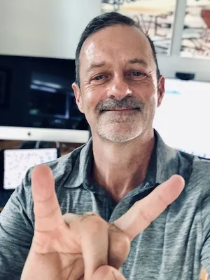 Dr. Richburg smiling and giving the Hook 'em Horns hand gesture.