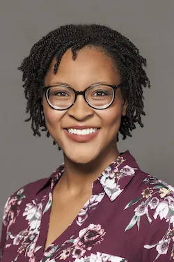 A woman wearing glasses and smiling.