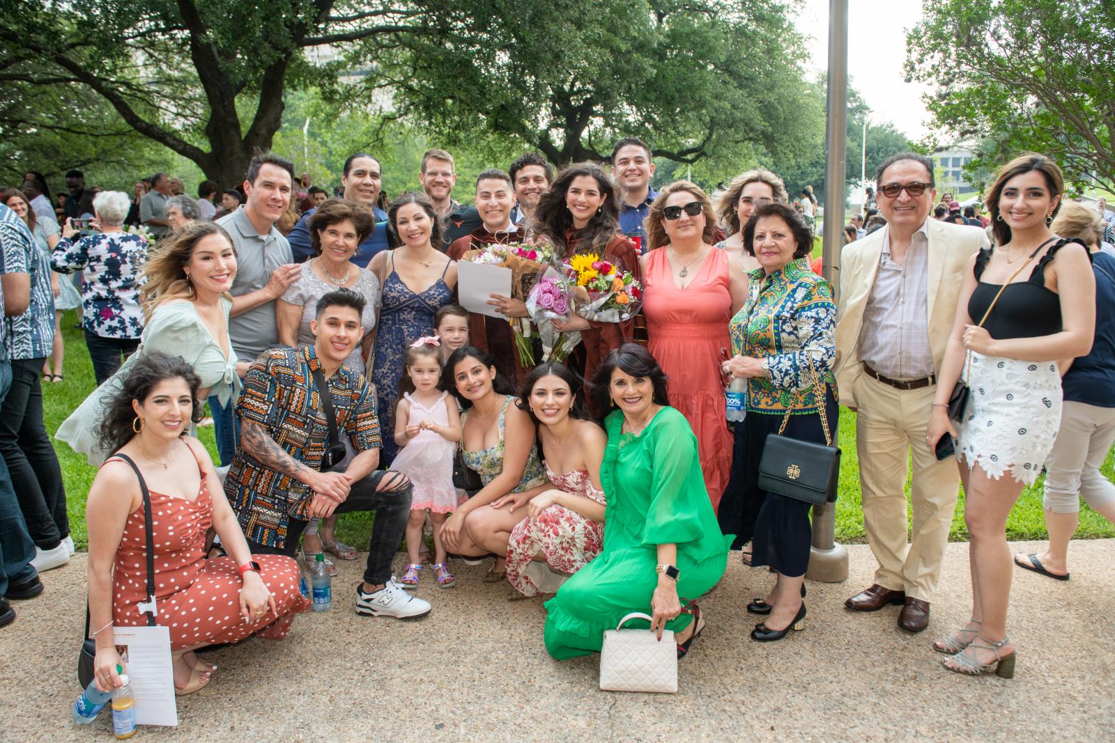 Family posing with recent graduate outside.