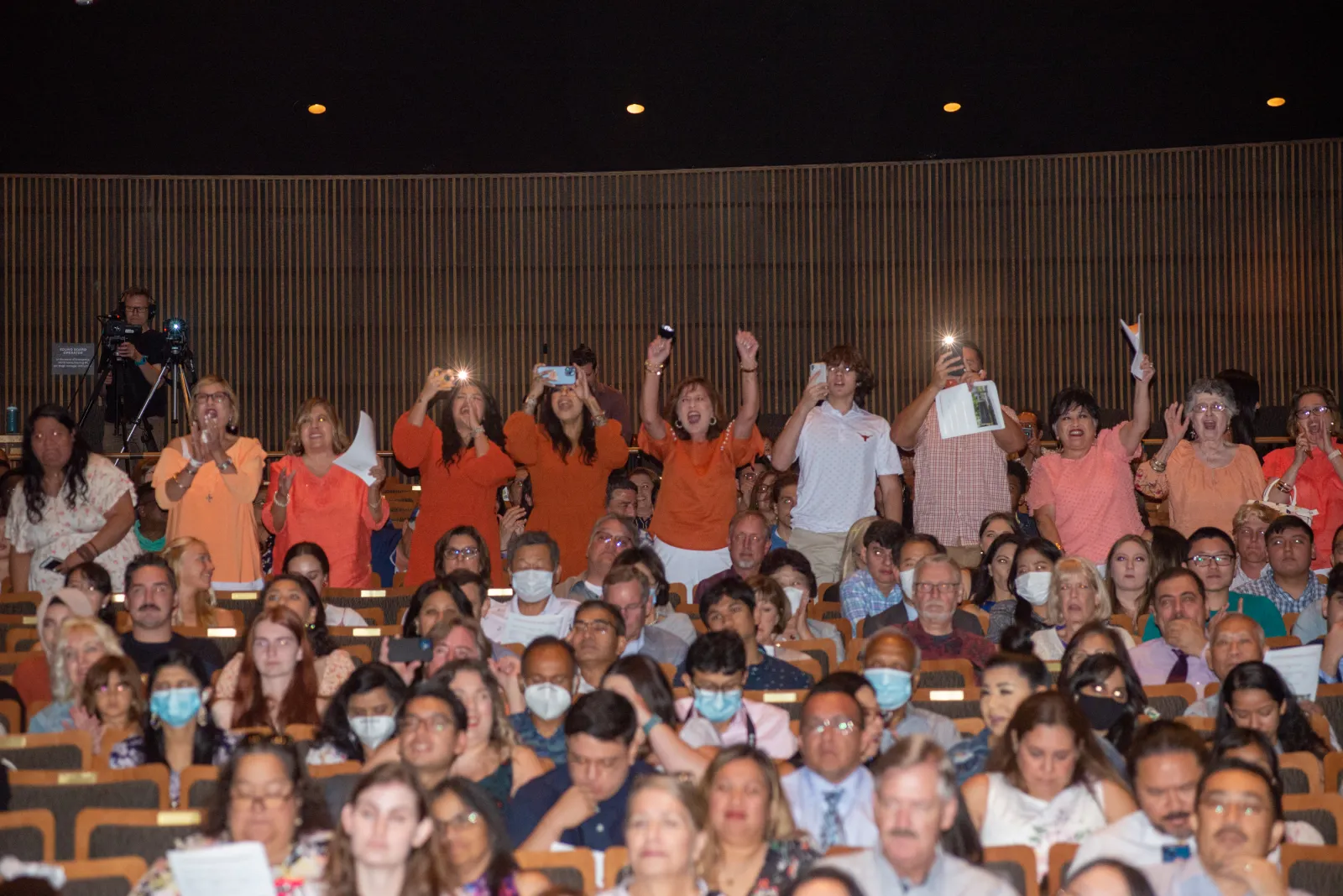 Family members taking photo of graduate walking across stage.