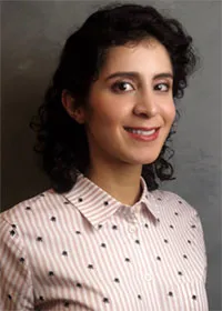 Elham Heidari smiling and wearing a patterned blouse