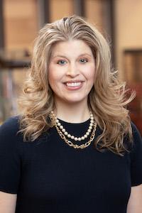 Dr. Moczygemba wearing necklaces and dark clothing and smiling.