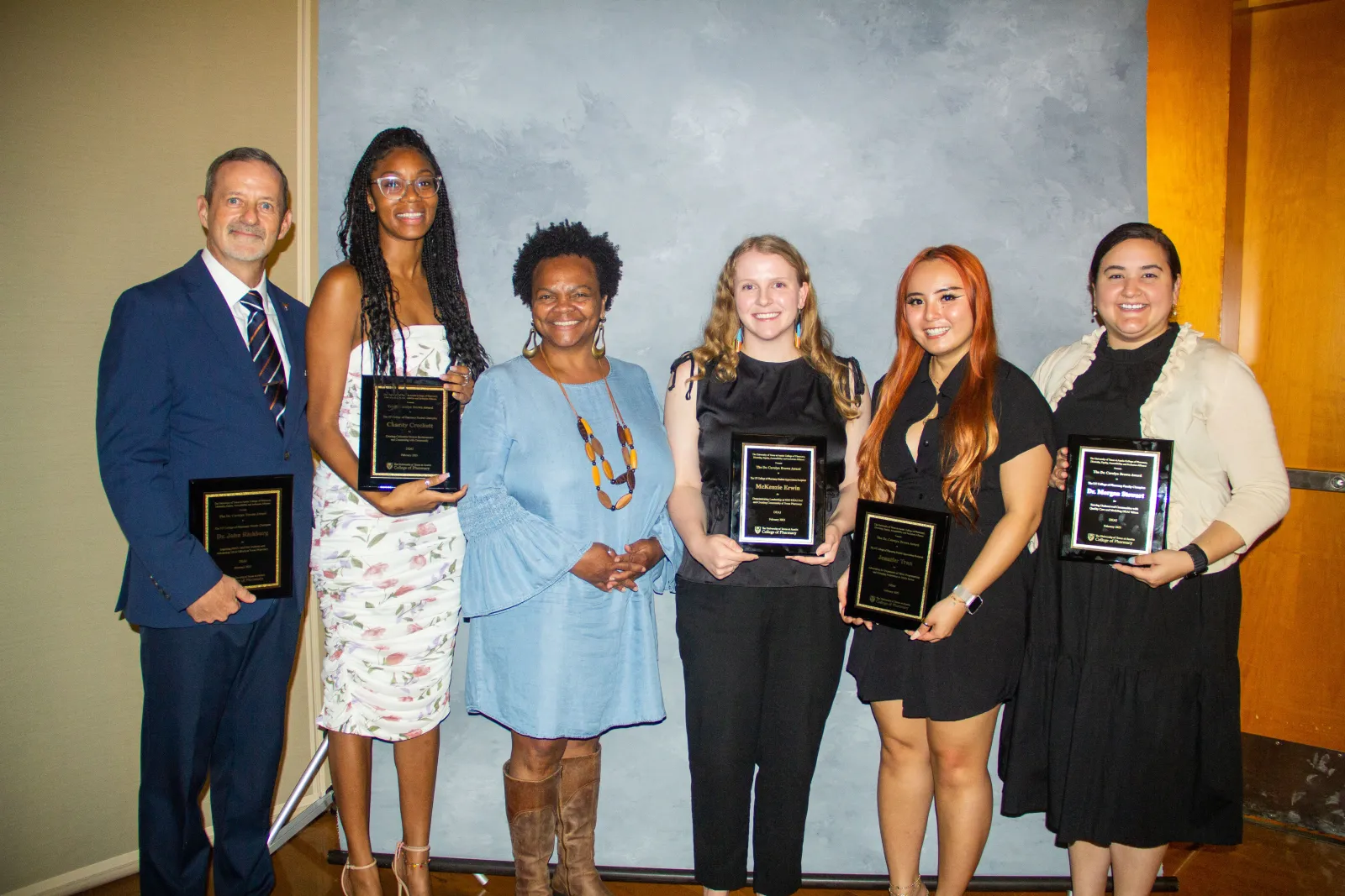 The DEAI Champion award winners standing together holding their plaques.
