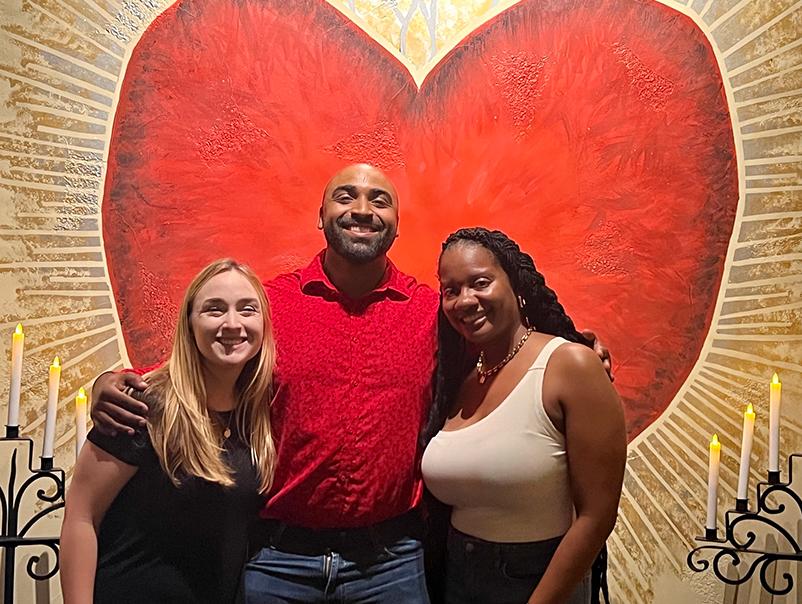 Group photo of 2022-2023 residents standing in front of a wall with a large heart and candles