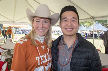 Two alumni smiling at homecoming tailgate event