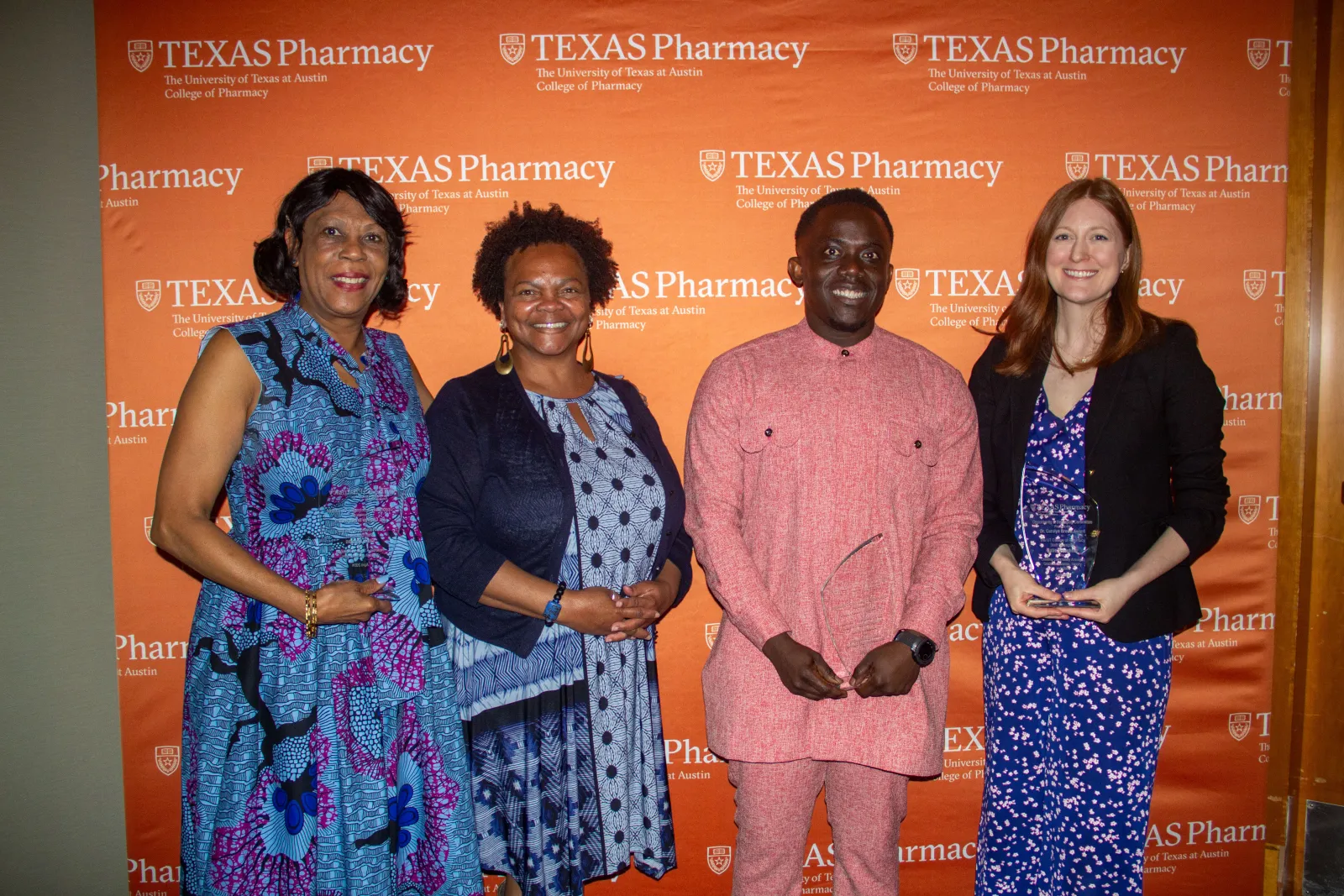 A group of people standing in front of a backdrop and holding awards.