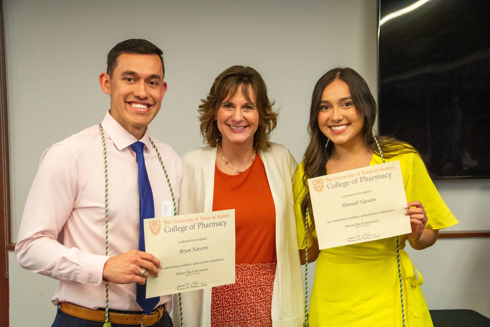 Three people holding certificates and smiling.