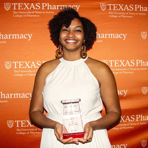 A woman holding an award and smiling.