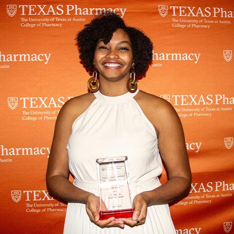 A woman holding an award and smiling.