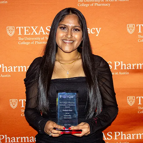 A woman smiling and holding an award.