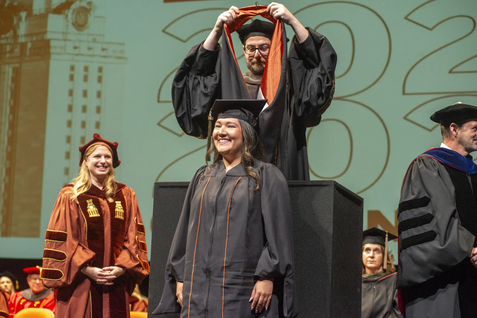 A graduate student wearing regalia and being hooded.