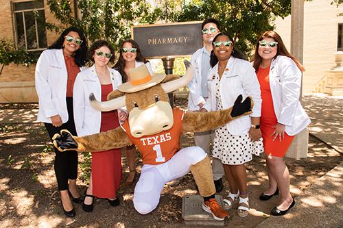 Pharmacy students and Bevo, the mascot, standing in front of the Pharmacy sign and Pharmacy building